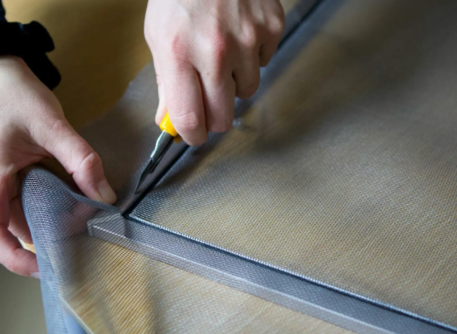 Technician re-meshing a window screen frame